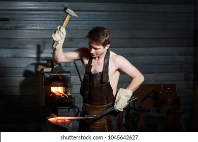 Blacksmith forging the molten metal on the anvil in smithy. - Powered by Shutterstock