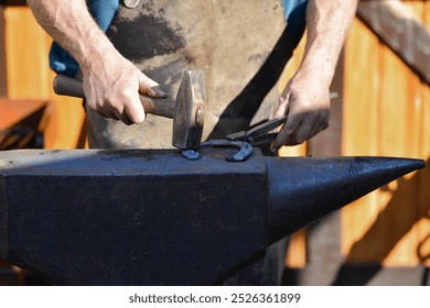 Blacksmith with a hammer working on a horseshoe - Powered by Shutterstock