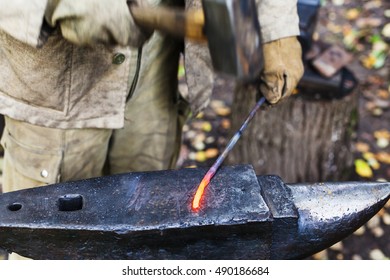 Blacksmith Hammering Red Hot Iron Rod On Anvil In Outdoor Rural Smithy