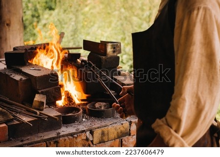 A blacksmith hardens steel at high temperature in a homemade furnace in the village