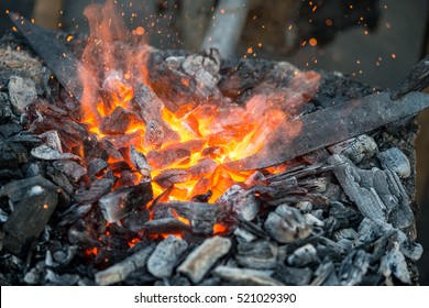 Blacksmith heats a blank for the knife in hot coals in the forge, close-up - Powered by Shutterstock