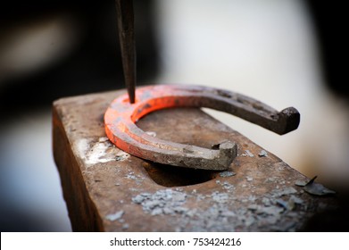 The blacksmith kicks a horseshoe close up .