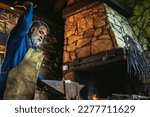 Blacksmith manually forging the molten metal on the anvil in smithy with spark fireworks