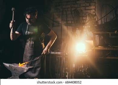 blacksmith manually forging the molten metal on the anvil in smithy with spark fireworks - Powered by Shutterstock