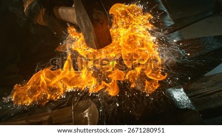 The blacksmith manually forging the molten metal on the anvil in smithy with spark fireworks. Action shot, cinematic and dramatic lights. Freeze motion.