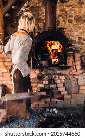 A Blacksmith In An Old Authentic Forge Using Medieval Technology Heats Metal In A Forging Furnace