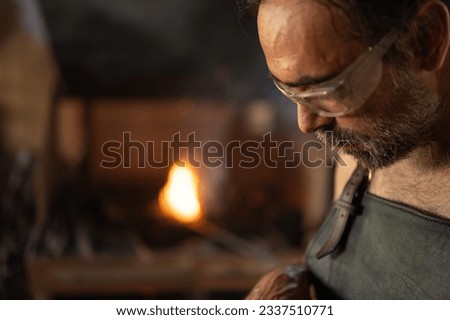 Blacksmith portrait with the forge in the background in his workshop. Blacksmith concept.