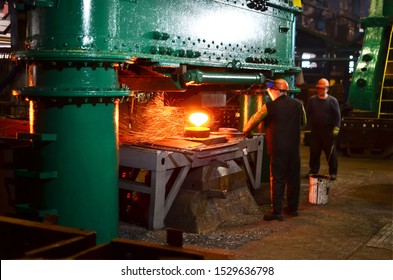 Blacksmith Processes The Red Hot Iron Under A Huge Press. Metal Forging, Stamping Under Hammer Forge At Workshop Of Forge Foctory. Blacksmithing, Metallurgical, Steelmaking, Hot Rolling Mill