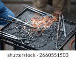 Blacksmith tools with forging fire and metalwork equipment in workshop.