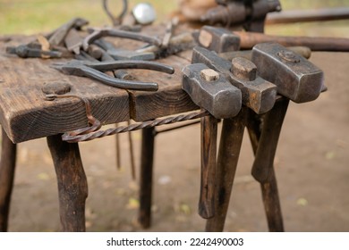 Blacksmith tools and instruments on wooden workbench, table at outdoor forge, workshop - close up. Handmade, craftsmanship and blacksmithing concept - Powered by Shutterstock