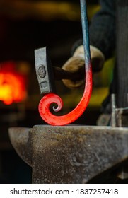 The blacksmith twists the spiral with a sledgehammer, placing a red-hot iron blank on the anvil. Work in the forge