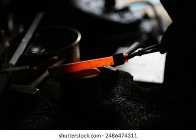 The blacksmith uses iron tongs to manage the shape of the Red hot metal - Powered by Shutterstock