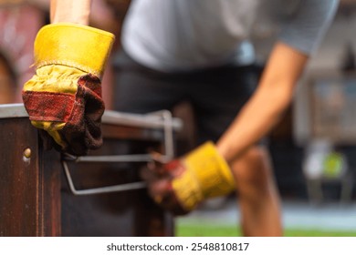 Blacksmith wearing protective gloves adding coal to forge to increase temperature for metalworking - Powered by Shutterstock