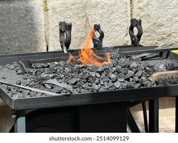 Blacksmithing forge, burning coal with blacksmith tools, traditional craftsmanship in a forge workshop, forge workshop concept - Powered by Shutterstock