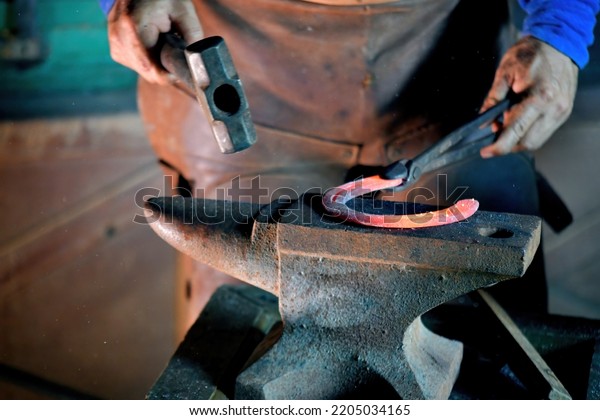 Blacksmith\'s hands at work In one hand is a\
hammer. The other side is a red hot metal\
piece.