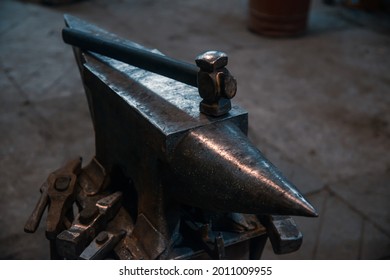 The blacksmith's tools are hung around the anvil, and the hammer is on top.