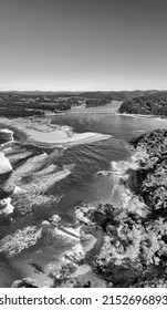 Black-white constrast landscape of Bega river delta on Sapphire coast of Pacific entering the ocean - aerial vertical panorama to bridge and rocks.