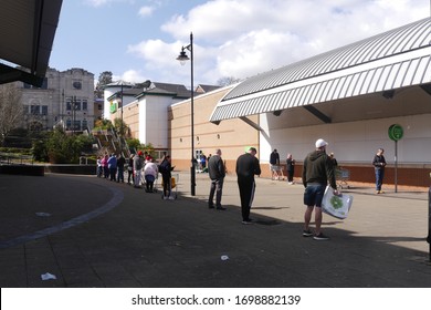 BLACKWOOD, WALES, UK - APRIL 6th 2020: Shoppers In A Very Long Queue Outside An ASDA Supermarket In South Wales During The Coronavirus Pandemic