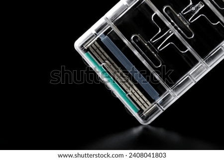 Blade attachment on a modern men's razor in a transparent container on a black background. Photo. Macro. Selective focus. Close-up