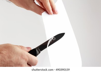 the blade of a sharp knife cut across the white paper