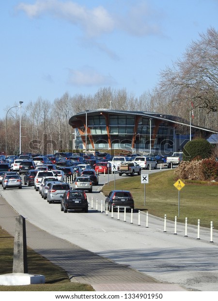 Blaine, WA / USA - 3/9/2019: The border crossing\
between Canada and the US at Blaine, WA and Surry BC. Cars wait in\
line to enter the canadian border patrol headquarters and border\
monument in view.