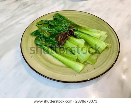 Blanch vegetable (Bok Choy) garnished with fried onion on a plate.