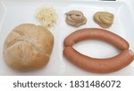 Bland and unappetizing hard bread roll with 2 boiled sausages and mustard sauces. 