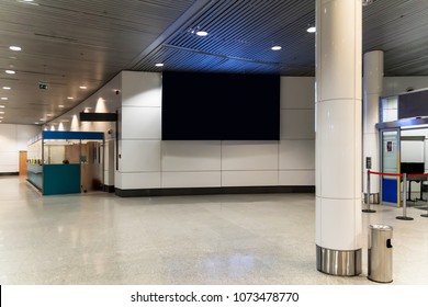 Blank Advertising Panel On Airport. A Large Black Screen On A White Wall In The Waiting Room Of Bus Terminal Or Train Station. Billboard In A Public Place