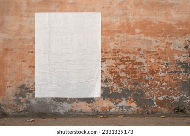 blank advertising poster glued to the weathered wall - copy space in pasted billboard on peeling plaster 