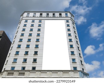 Blank advertising vertical banner poster mockup on modern tall building facade exterior. Super large billboard, out-of-home OOH media display space.