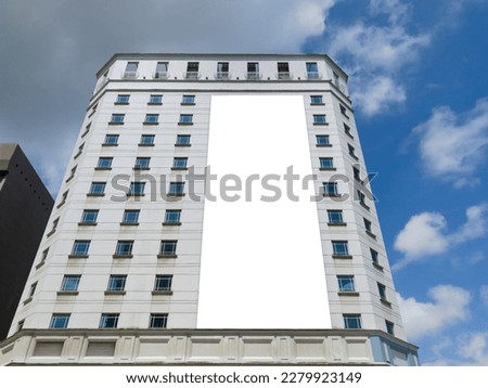 Blank advertising vertical banner poster mockup on modern tall building facade exterior. Super large billboard, out-of-home OOH media display space.