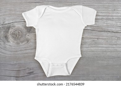 Blank Baby Onesie Lying Flat On A Weathered Gray Wooden Background.