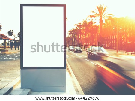 Blank billboard with copy space for your text message or content, outdoors advertising mock up, public information board on city road, flare sun light and motion blur effect with ride cars and taxi