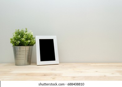 Blank Black Frame Mock Up White Picture Frame With Mini Leaf Green Plant Tree In Silver Pot Small Home Decorative On Wooden Desk With White Wall Background, Home Decoration Concept, Copy Space