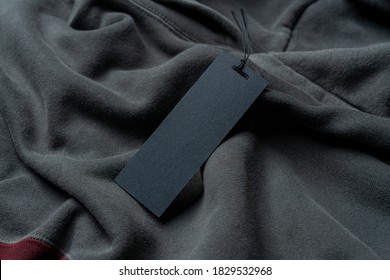 Blank Black Rectangular Clothing Tag, Label Mockup Template On Gray And Tile Colored Stylish Sportswear. Price Tag Label With Copy Space, Empty Space.