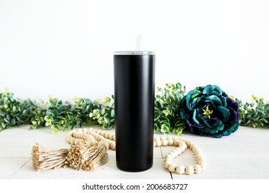 Blank black skinny tumbler on white wood background with beed decor, drinkware mockup