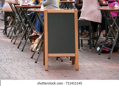 Blank Blackboard Advertising Sign Or Customer Stopper At Sidewalk Cafe