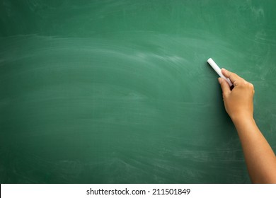 Blank blackboard / chalkboard, hand writing on green chalk board holding chalk, great texture for text - Powered by Shutterstock