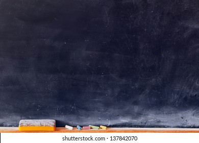Blank blackboard with colored chalks and eraser. Horizontal composition.
