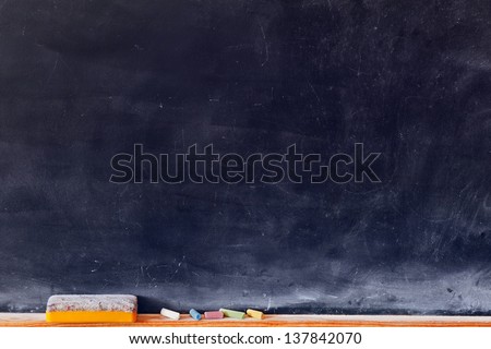 Blank blackboard with colored chalks and eraser. Horizontal composition.