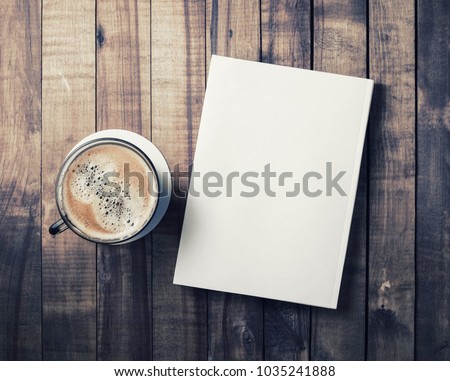 Blank book and coffee cup on vintage wood background. Responsive design template. Flat lay.