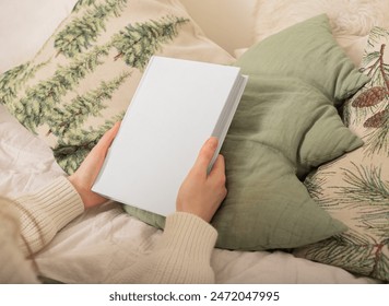 Blank book mockup with cover. Hand holding white paper template. Woman s background design for empty female business. Cozy warm bed with pillow view. Hold closed diary page