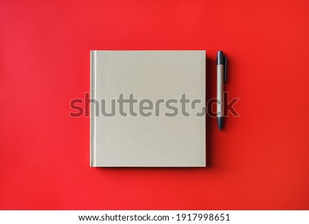 Blank book and pen on red paper background. Blank branding template. Mockup for branding identity for placing your design. Flat lay.