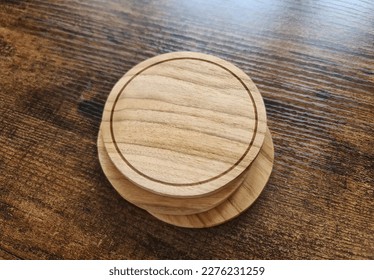 Blank brown coaster stack mockup with wood texture on wooden surface. Circular drink pad pile template