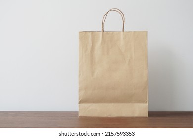 Blank Brown Paper Bag On Wooden Table. Mockup For You Designs.