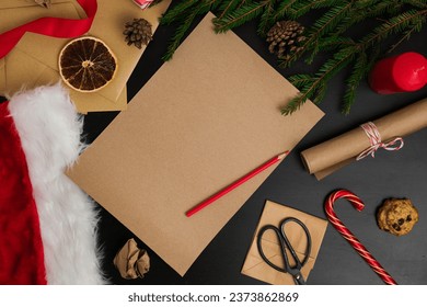 Blank Brown Paper Page on Black Wood Table with Christmas Decoration. Mock Up of Letter to Santa Claus. Top View of Jolly Father Desk with Envelopes, Fir Branches, Xmas Ornament. View from Above. - Powered by Shutterstock