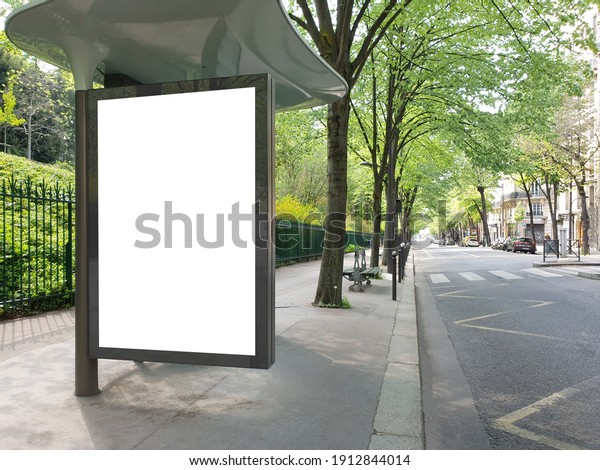 Blank bus stop billboard Mockup in empty street in\
Paris. Parisian style hoarding advertisement close to a park in\
beautiful city