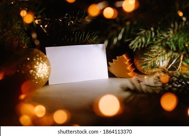 Blank Business Card With Christmas Tree Branches And Golden Garland Lights. New Year Celebration Concept Banner. Gift Certificate. Side View. Cozy Frame Decoration. Invitation To An Event Or Party.