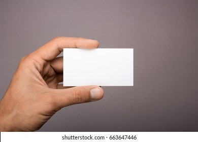 Blank Business Card In Hand On A Gray Background.  Mockup