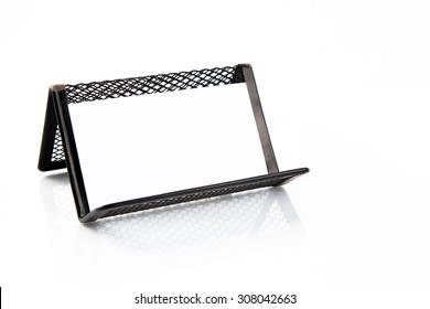 Blank business card on the holder on white background with reflection